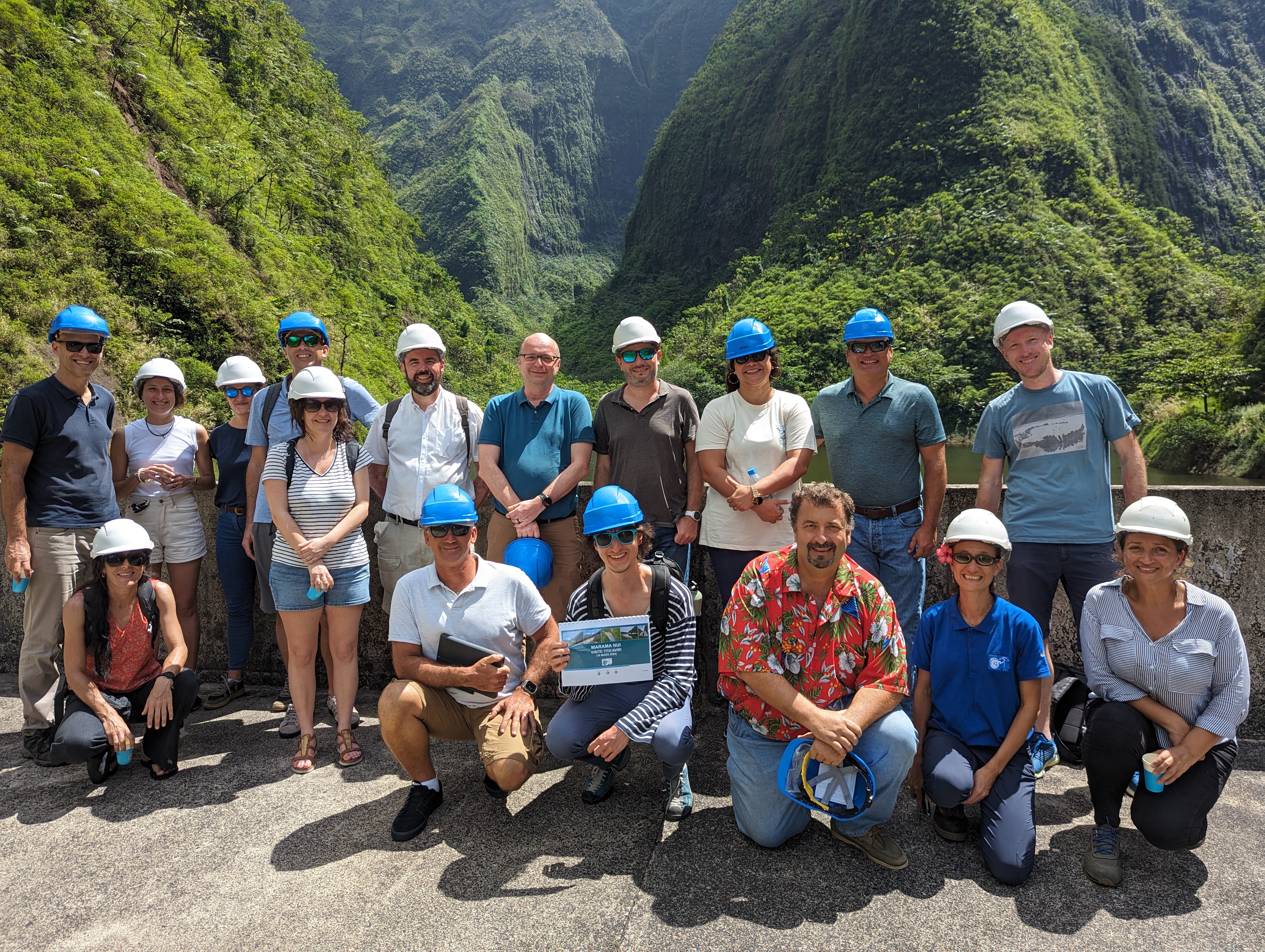 group picture in front of green mountains with people wearing safety helmets